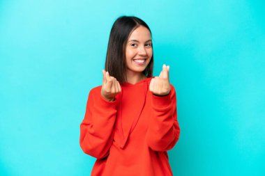 Mavi arka planda izole genç beyaz kadın para hareketi yapıyor.