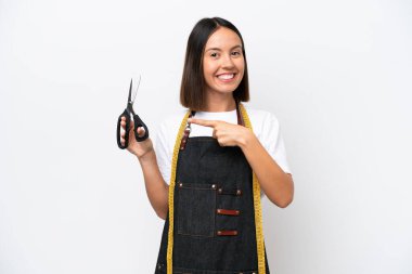 Young seamstress woman isolated on white background pointing to the side to present a product