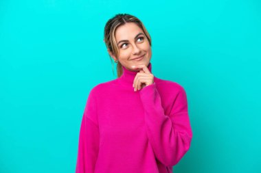 Genç beyaz kadın mavi arka planda izole edilmiş ve yukarı bakıyor.