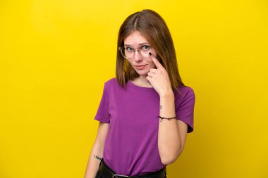 Sarı arka planda izole edilmiş genç İngiliz kadın bir şey gösteriyor.