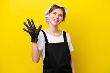 Sarı arka planda izole edilmiş genç İngiliz balıkçı parmaklarıyla beşi sayıyor.