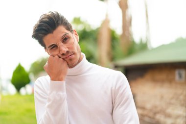 Genç, beyaz, gözlüklü, üzgün yüzlü bir adam.