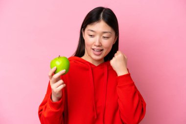 Pembe arka planda izole edilmiş genç bir Çinli kadın zaferi kutluyor.