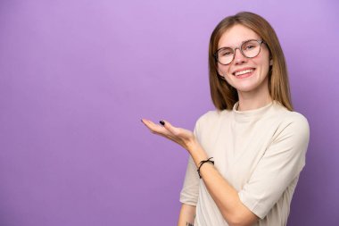 Mor arka planda izole edilmiş genç bir İngiliz kadın gülümserken bir fikir sunuyor.