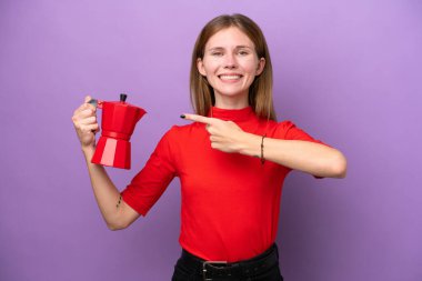 Mor arka planda izole edilmiş kahve makinesini tutan genç İngiliz kadın.