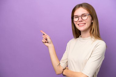 Mor arka planda izole edilmiş genç bir İngiliz kadını işaret ediyor.