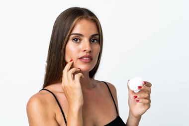 Genç Uruguaylı kadın, beyaz arka planda nemlendirici ile izole edilmiş.