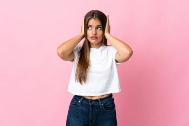 Genç Uruguaylı kadın pembe arka planda izole edilmiş hayal kırıklığına uğramış ve kulaklarını kapatmış.