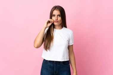 Pembe arka planda izole edilmiş genç Uruguaylı kadın sessizlik işareti gösteriyor.