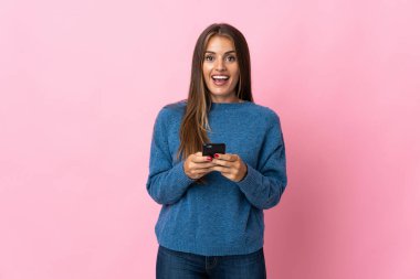 Pembe arka planda izole edilmiş genç Uruguaylı kadın şaşırdı ve bir mesaj gönderiyor.