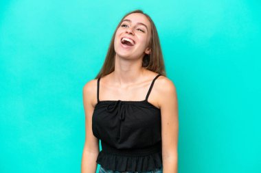 Mavi arka planda izole edilmiş genç beyaz kadın gülüyor.