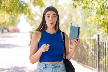 Pasaportu elinde tutan genç, güzel Brezilyalı kadın şaşırmış ve ön tarafı işaret ediyor.