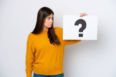 Genç Brezilyalı bir kadın beyaz arka planda izole edilmiş. Elinde soru işareti olan bir levha var.