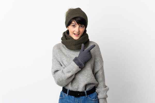 Young girl with winter hat pointing to the side to present a product