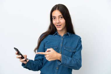 Genç Fransız kız beyaz arka planda cep telefonu kullanarak izole edilmiş ve onu işaret ediyor.