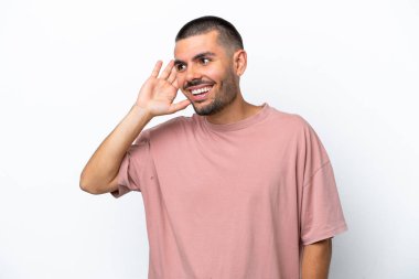 Beyaz arka planda izole edilmiş genç beyaz bir adam. Kulağına elini sürerek bir şeyler dinliyor.