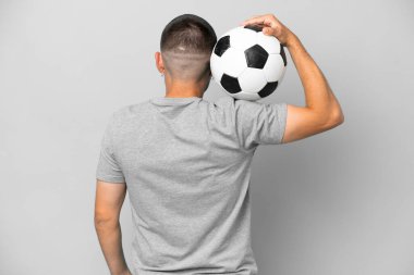 Genç futbolcu, gri arka planda futbol topuyla izole edilmiş.