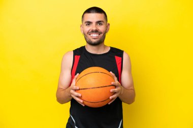 Sarı izole edilmiş arka planda basketbol topu olan yakışıklı bir basketbolcu.