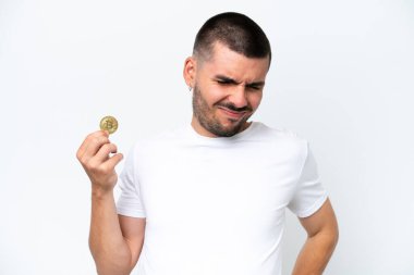 Beyaz arka planda bitcoin tutan beyaz tenli genç beyaz adam çaba sarf ettiği için sırt ağrısı çekiyor.