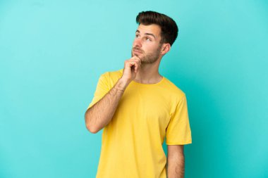 Beyaz tenli yakışıklı bir adam mavi arka planda izole edilmiş ve yukarı bakıyor.