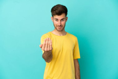 Beyaz tenli yakışıklı bir adam mavi arka planda izole edilmiş ve bizimle gelmesi için davet ediliyor. Gelmene sevindim.