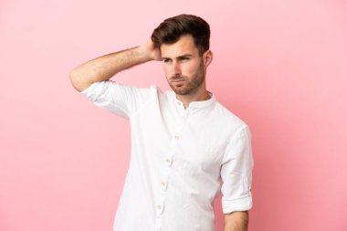 Young caucasian handsome man isolated on pink background having doubts while scratching head
