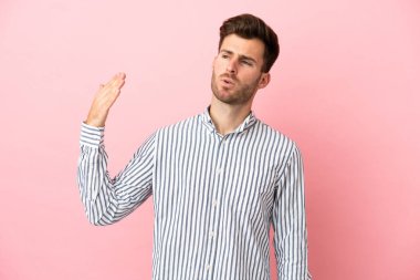 Pembe arka planda izole edilmiş, yorgun ve hasta bir ifadeyle genç, beyaz, yakışıklı bir adam.