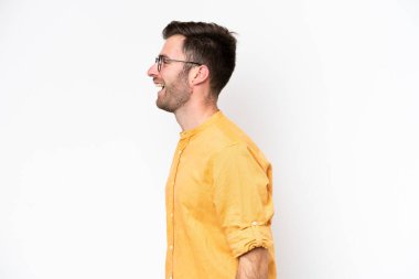 Beyaz arka planda izole genç beyaz adam yan pozisyonda gülerek