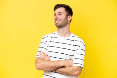 Sarı arka planda izole edilmiş genç beyaz adam mutlu ve gülümsüyor.