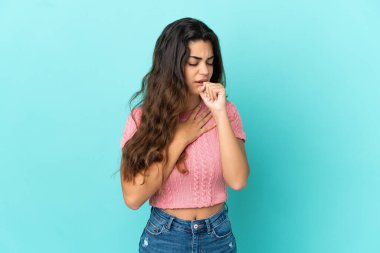 Mavi arka planda izole edilmiş genç beyaz kadın çok öksürüyor.