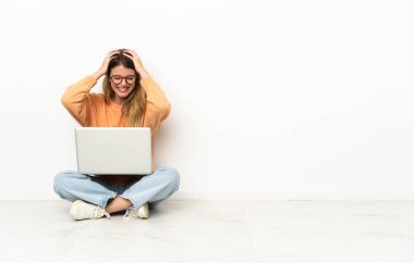 Yerde oturan dizüstü bilgisayarı yla gülen genç kadın