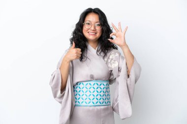 Kimono giyen genç Asyalı kadın beyaz arka planda izole edilmiş. Tamam işareti gösteriyor.