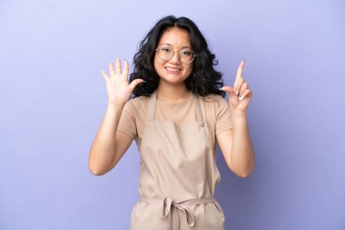 Restoran Asyalı garson, mor arka planda yediyi parmaklarıyla sayıyor.