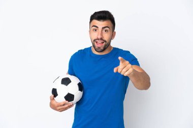 Yakışıklı genç futbolcu, ıssız bir duvarın üstünde şaşırmış ve ön tarafı işaret ediyor.