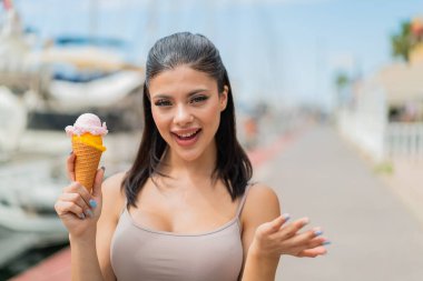 Açık havada kornet dondurması olan genç ve güzel bir kadın. Yüzünde şok ifadesi var.