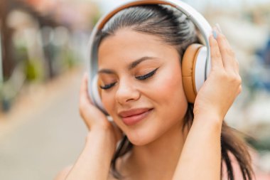 Açık havada müzik dinleyen genç ve güzel bir kadın.