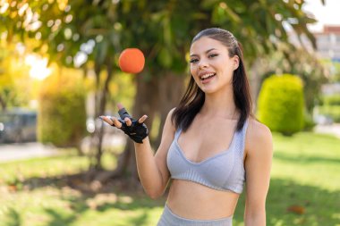 Açık havada elinde portakalla gezen genç ve güzel bir bayan.