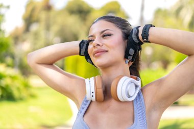 Açık havada genç ve güzel bir bayan spor giyer.