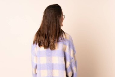 İzole edilmiş bej arka planda genç bir kadın var.