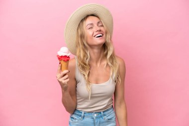 Pembe arka planda izole edilmiş dondurma tutan genç Rus kadın gülüyor.