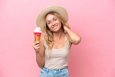 Pembe arka planda izole edilmiş dondurma tutan genç Rus kadın gülüyor.