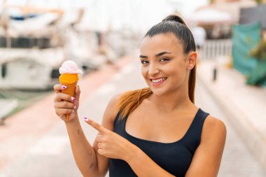 Açık havada kornet dondurması olan genç ve güzel bir kadın.