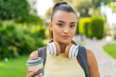 Dışarıdaki güzel kadın elinde kahve tutuyor.