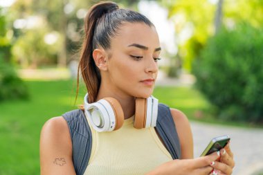 Dışarıda cep telefonu kullanan genç ve güzel bir kadın.