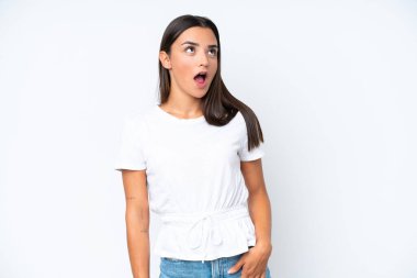 Beyaz arka planda izole edilmiş genç beyaz kadın yukarı bakıyor ve şaşırmış bir ifadeyle