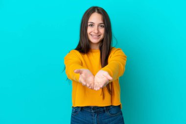 Mavi arka planda izole edilmiş genç Ukraynalı bir kadın bir ilan vermek için avucunun içinde hayali bir kopyalama alanı tutuyor.