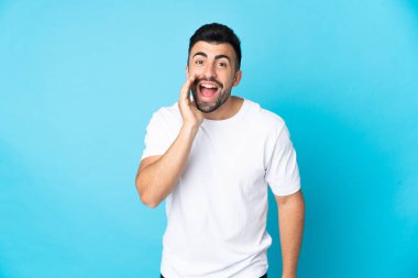 İzole edilmiş mavi arka planda beyaz bir adam ağzı açık bağırıyor.