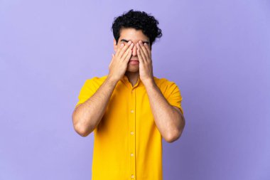 Genç Venezuelalı adam mor arka planda izole edilmiş gözleri elleriyle kaplayan