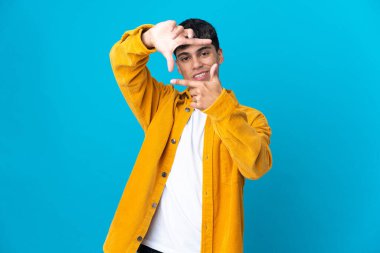 İzole edilmiş mavi arka planda odaklanan genç bir adam. Çerçeve sembolü