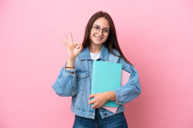 Pembe arka planda izole edilmiş genç Ukraynalı kadın parmaklarıyla tamam işareti gösteriyor.